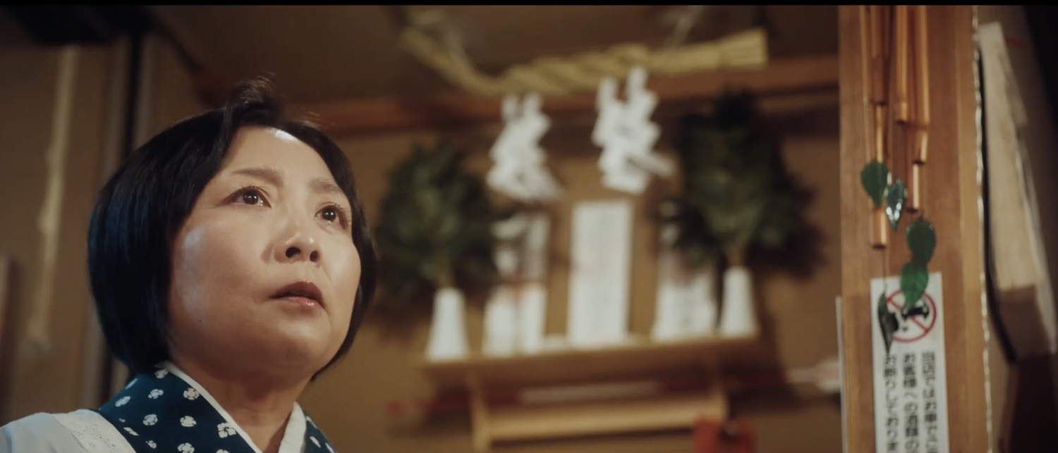 A woman looks upward with reverence inside a Japanese izakaya